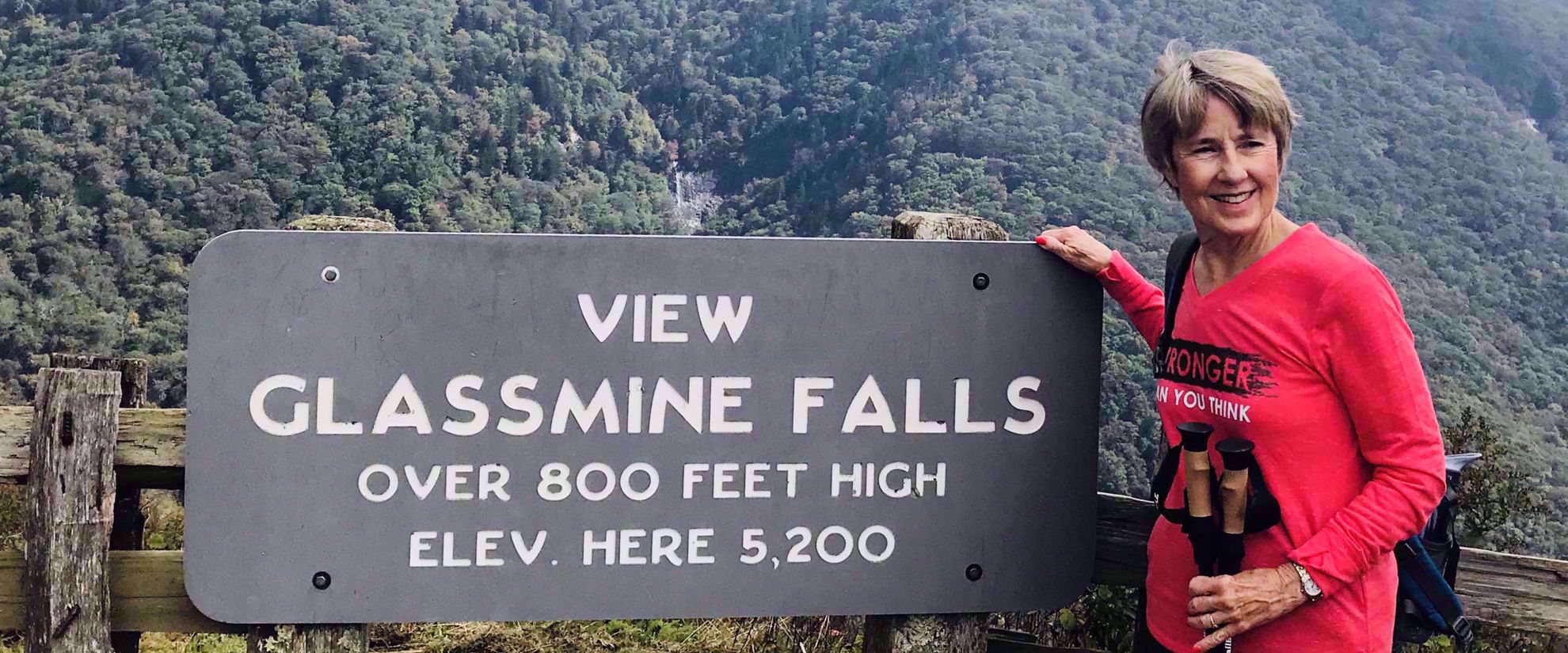 Woman smiling by Glassmine falls sign