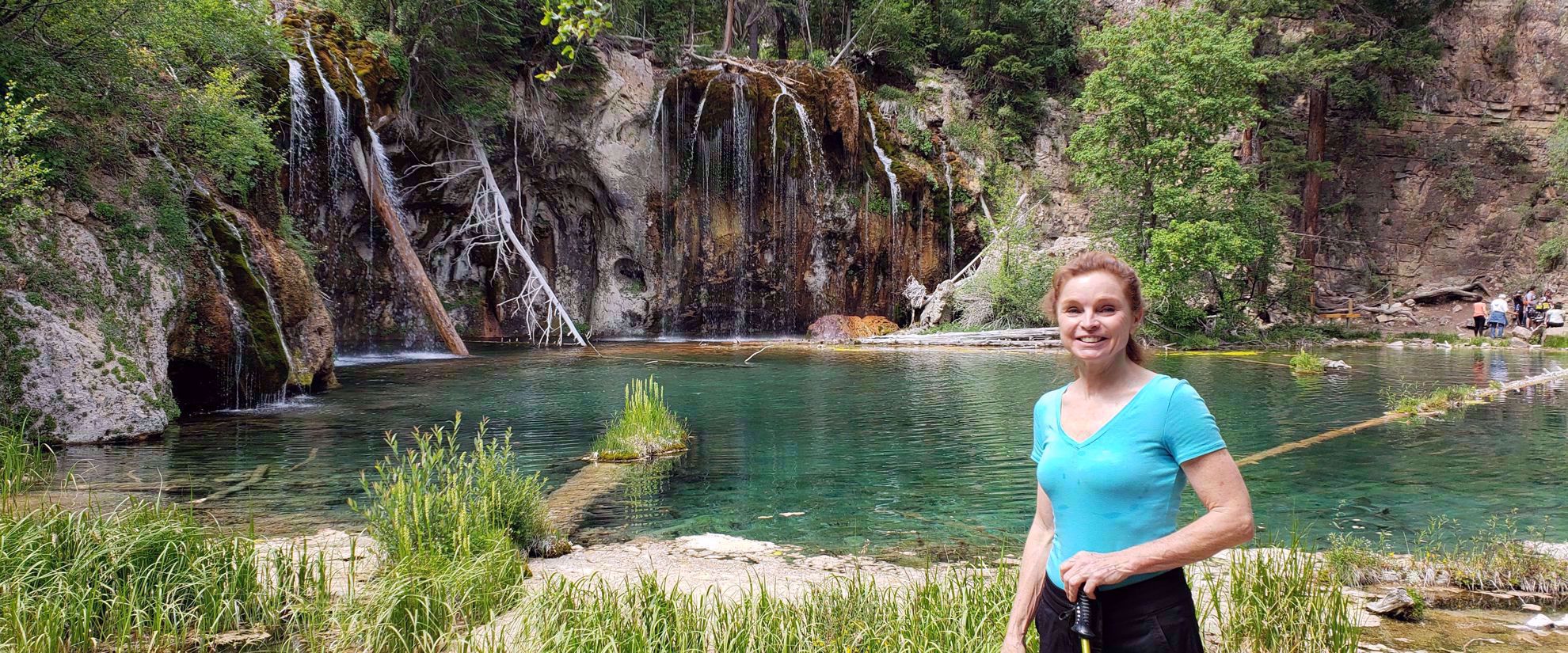 woman smiling by waterfall and lake in colorado