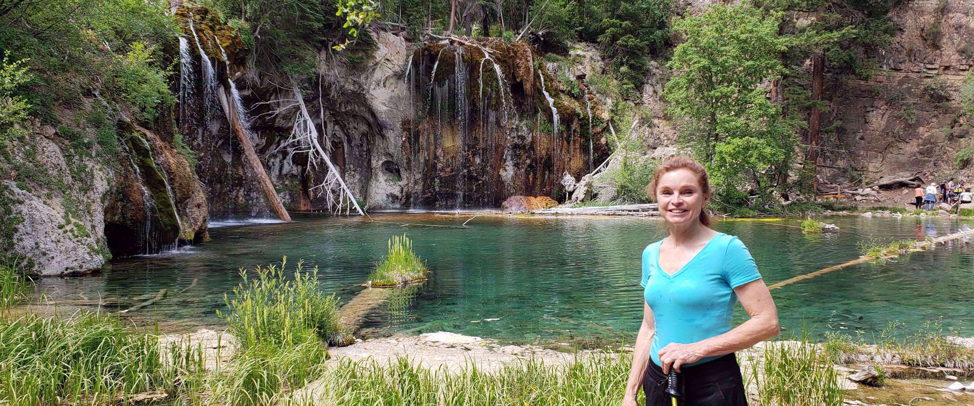 woman smiling by waterfall and lake in colorado