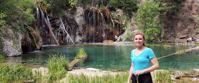 woman smiling by waterfall and lake in colorado