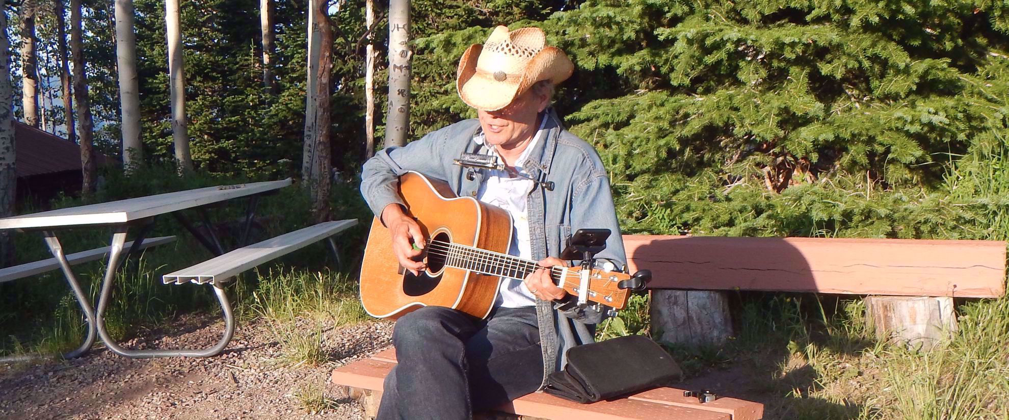 woman wearing hat playing guitar at camp site