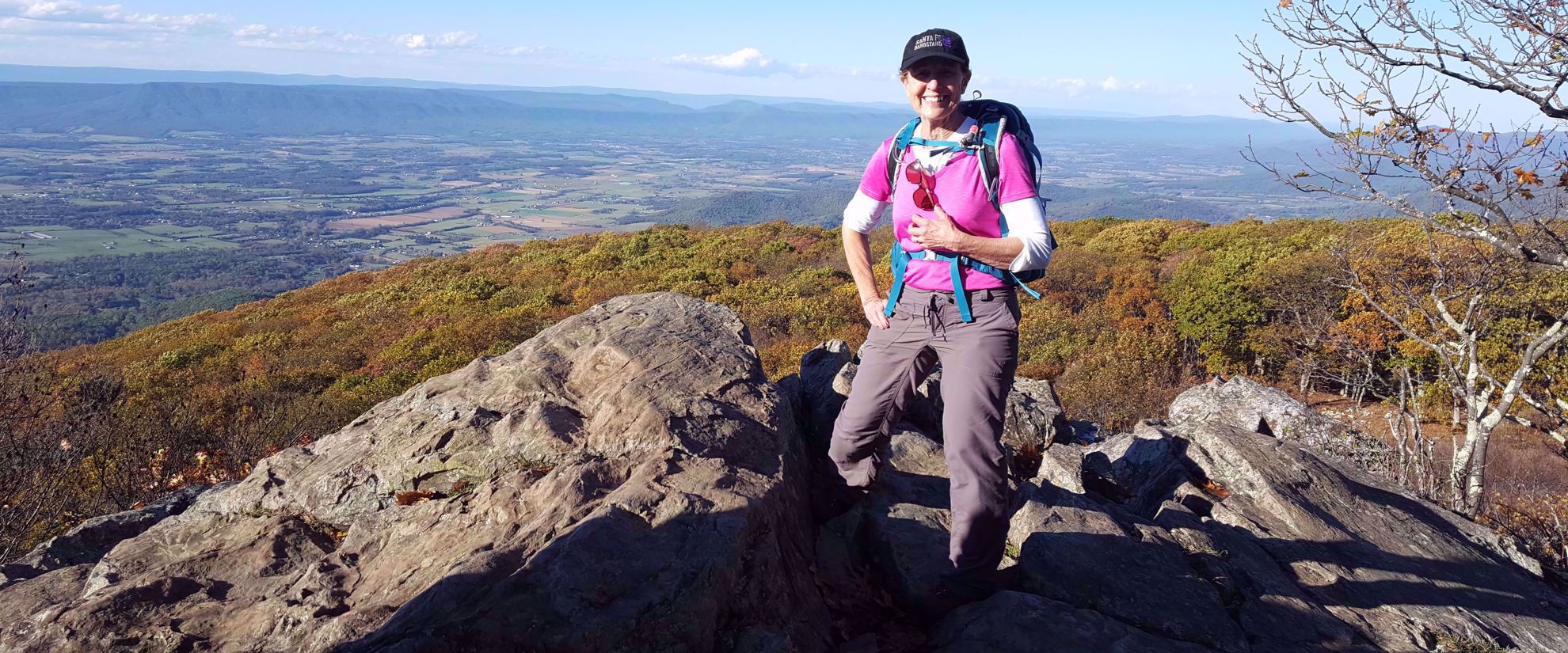 woman smiles on hike overlooking valley