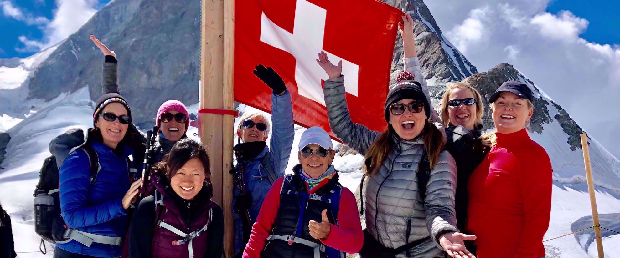 women smiling with swiss flag on group tour through swiss alps