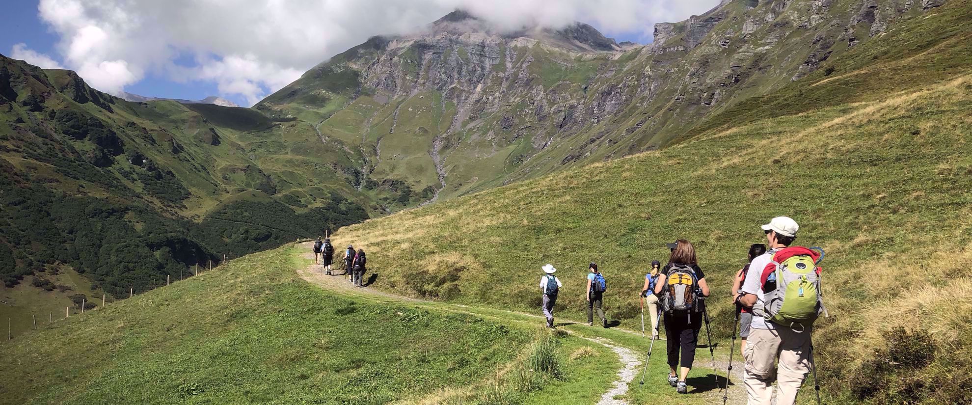women walking on grass path on group hike through swiss alps